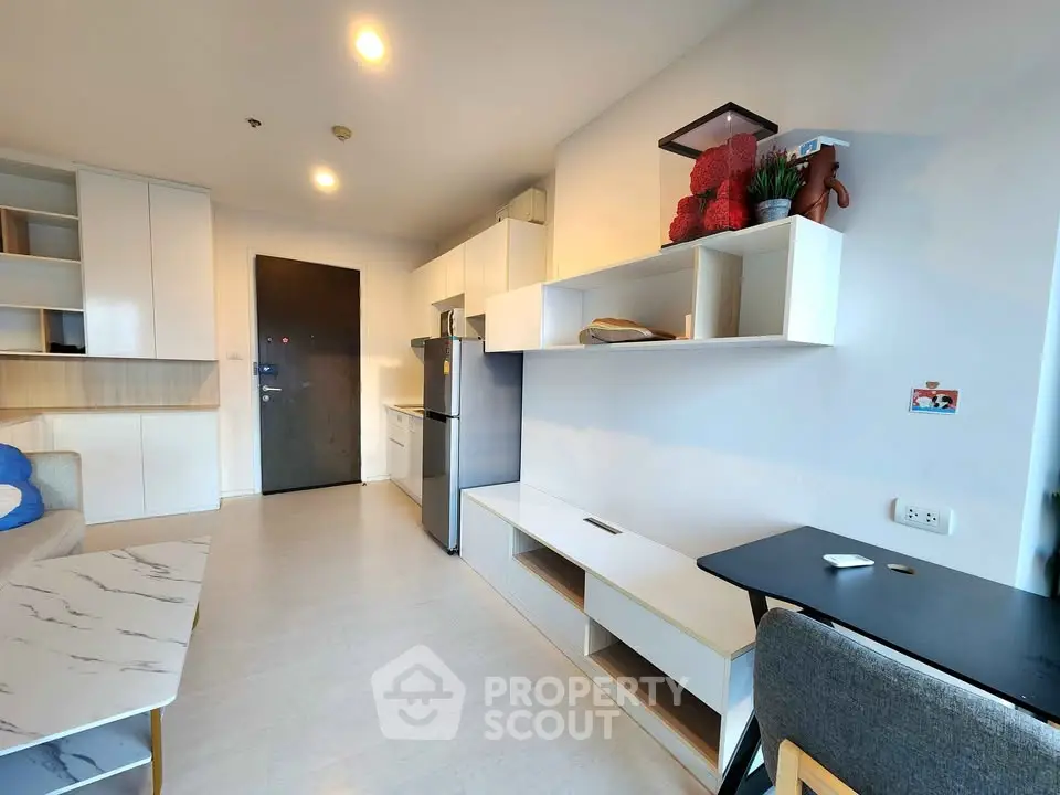 Modern living room with sleek furniture and open layout, featuring a stylish kitchen and cozy workspace.