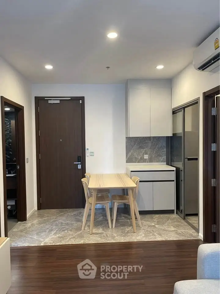 Modern apartment interior with compact kitchen and dining area, featuring sleek design and efficient use of space.