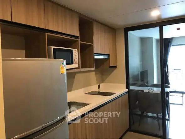 Modern kitchen with sleek wooden cabinets and glass sliding door leading to dining area.
