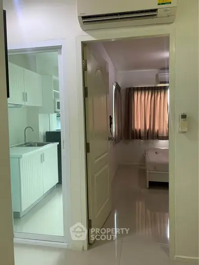 Modern apartment interior with sleek kitchen and cozy bedroom, featuring air conditioning and natural light.