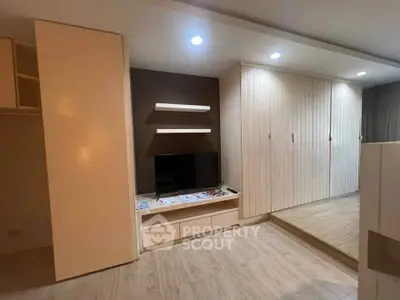 Modern living room with sleek built-in storage and TV unit, featuring warm lighting and wooden flooring.