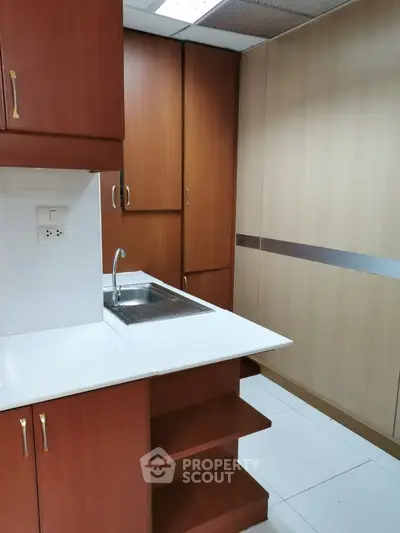 Compact kitchen with wooden cabinets and white countertops in modern apartment