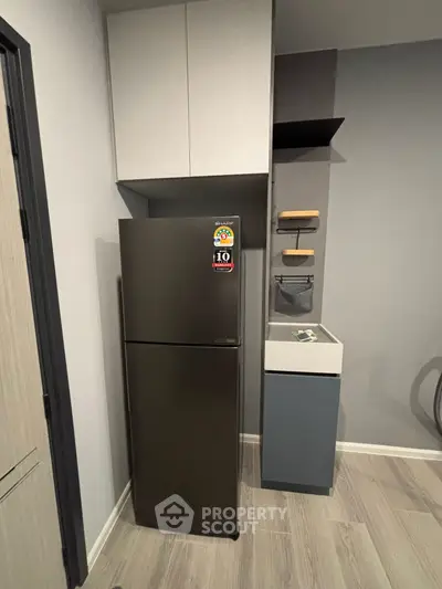 Modern kitchen corner with sleek fridge and stylish storage solutions.