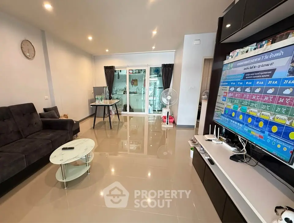 Spacious modern living room with sleek furniture and large TV, perfect for relaxation.