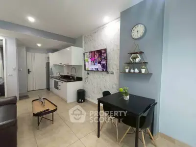 Modern open-layout living room with sleek kitchen and dining area, featuring stylish decor and wall-mounted TV.