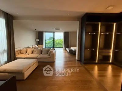 Spacious modern living room with large sofa and open view balcony, featuring elegant wooden flooring.