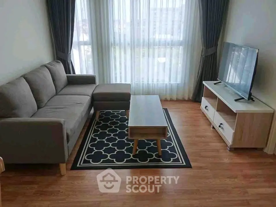 Modern living room with stylish sofa, TV stand, and large window for natural light.