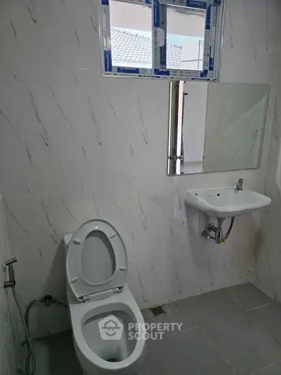 Modern bathroom with sleek white tiles and compact fixtures, perfect for contemporary living.