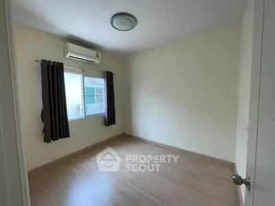 Spacious empty bedroom with wooden flooring and air conditioning