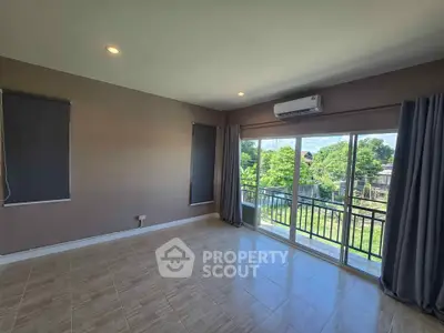 Spacious living room with large windows and balcony access, offering a serene view of greenery.