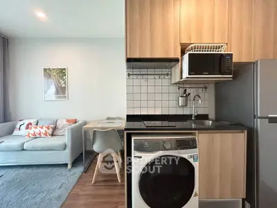 Modern open-plan living room and kitchen with sleek appliances and cozy seating area.