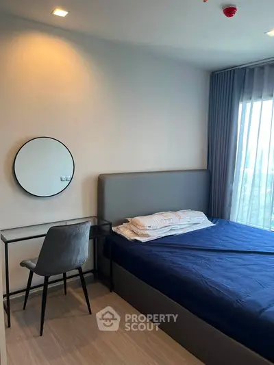 Modern bedroom with stylish decor and natural light, featuring a cozy bed and sleek desk.