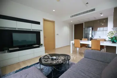 Modern living room with sleek furniture and open kitchen layout in a stylish apartment.