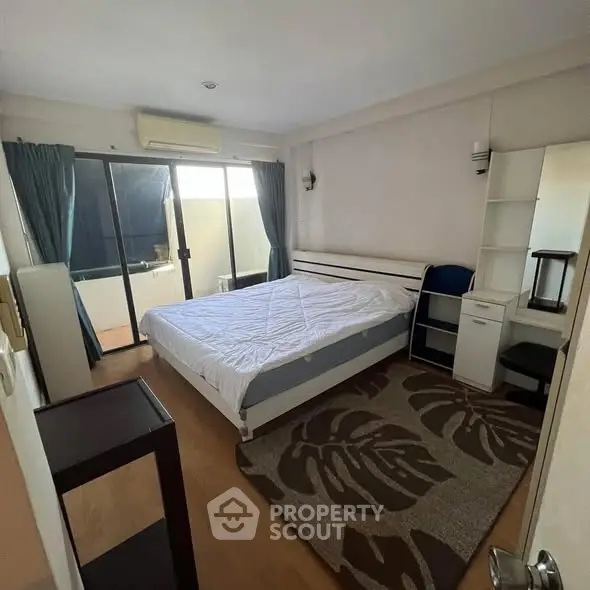 Spacious bedroom with balcony access and modern furnishings in a stylish apartment.