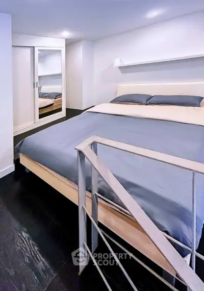 Modern bedroom with sleek design and mirrored closet doors, featuring a cozy bed and stylish railing.