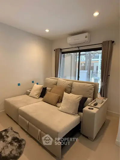 Cozy living room with plush sofa and air conditioning, perfect for relaxation.