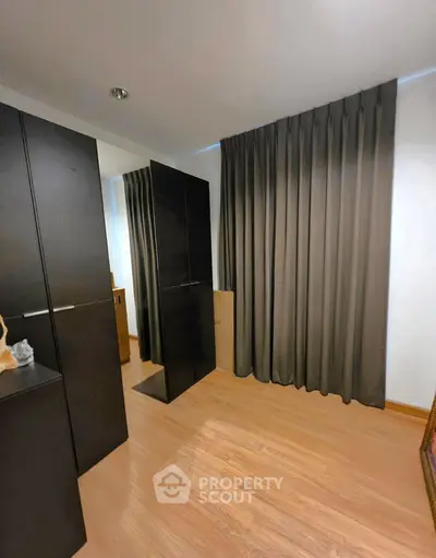 Spacious bedroom with elegant dark curtains and sleek wooden flooring