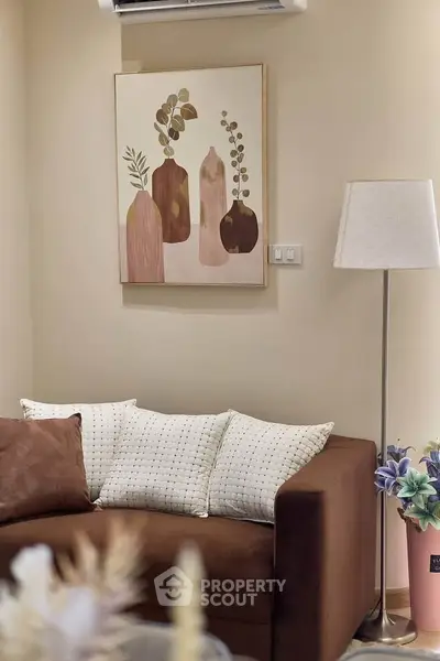 Cozy living room with modern decor, featuring a stylish brown sofa, elegant floor lamp, and chic wall art.