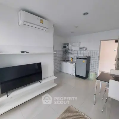 Modern apartment interior with sleek kitchen and cozy living area featuring a TV and air conditioning.