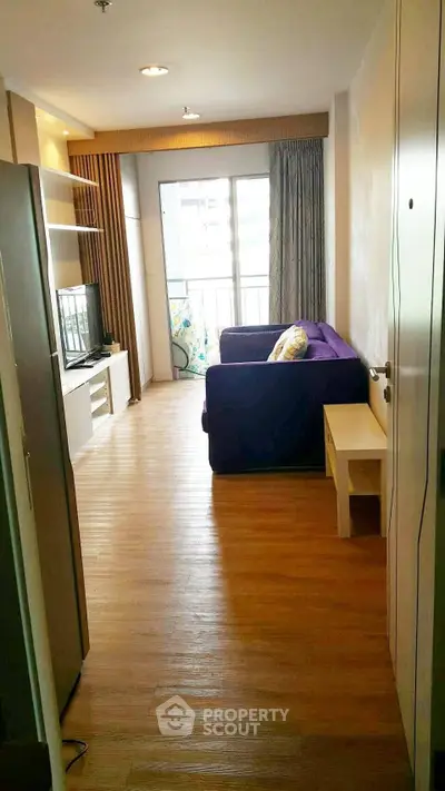 Modern living room with wooden flooring and balcony access in a stylish apartment.