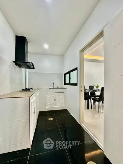 Modern kitchen with sleek black flooring and open layout to dining area