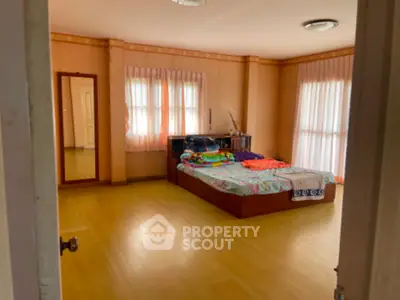 Spacious bedroom with polished wooden floors, ample natural light, and warm-toned walls, offering a serene and comfortable living space.