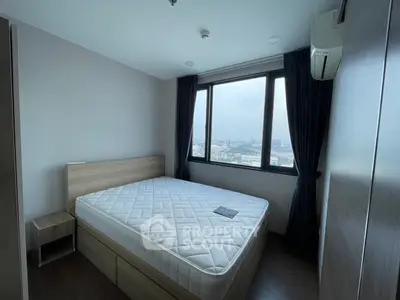 Modern bedroom with large window offering city views, featuring a comfortable bed and sleek design.