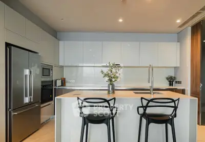 Modern kitchen with sleek cabinetry, island seating, and stainless steel appliances in a luxury apartment.
