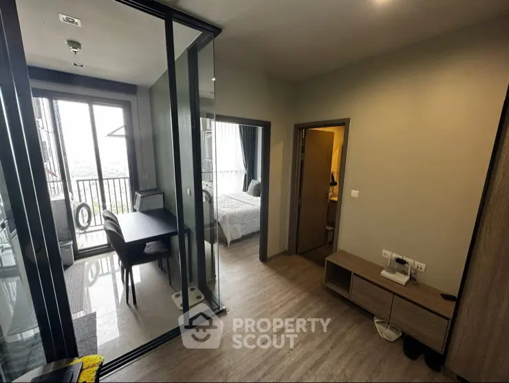Modern apartment interior with glass partition, cozy bedroom, and balcony view.