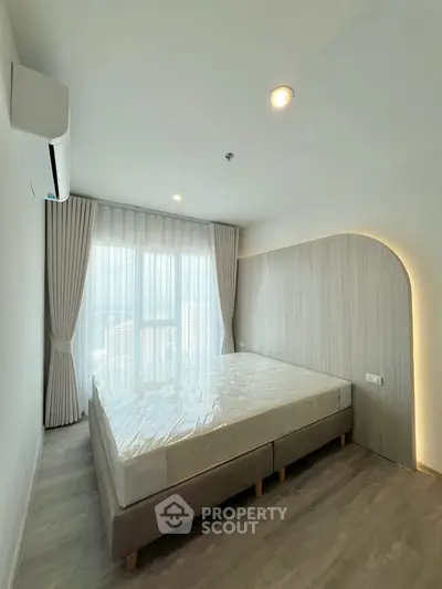 Modern bedroom with large window and stylish decor in a contemporary apartment.