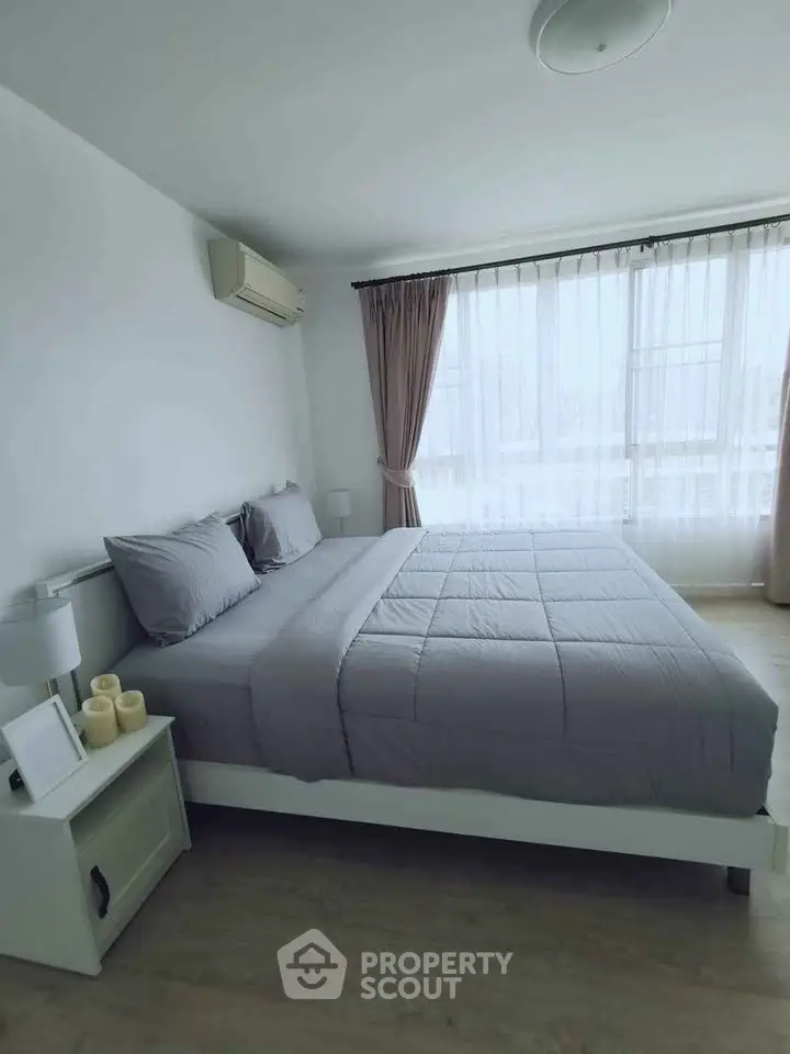 Spacious bedroom with large window and modern decor in a stylish apartment.