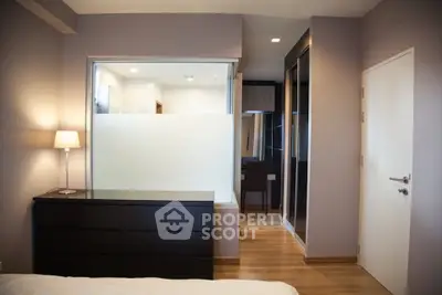Modern bedroom with sleek design and wooden flooring, featuring a stylish dresser and a cozy ambiance.