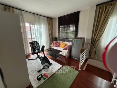 Charming living room with exercise bike and cozy seating area, perfect for relaxation and fitness.