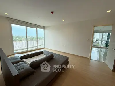 Spacious bedroom with stunning river view and large windows in modern apartment.