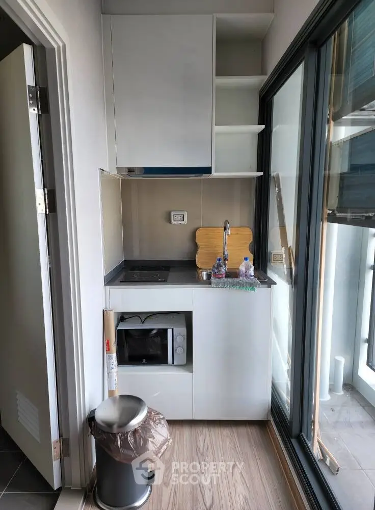 Compact modern kitchen with sleek cabinetry and balcony access, ideal for urban living.