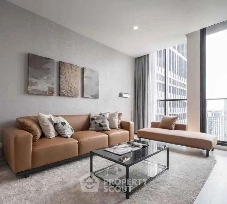 Modern living room with stylish furniture and city view, featuring a brown leather sofa and glass coffee table.