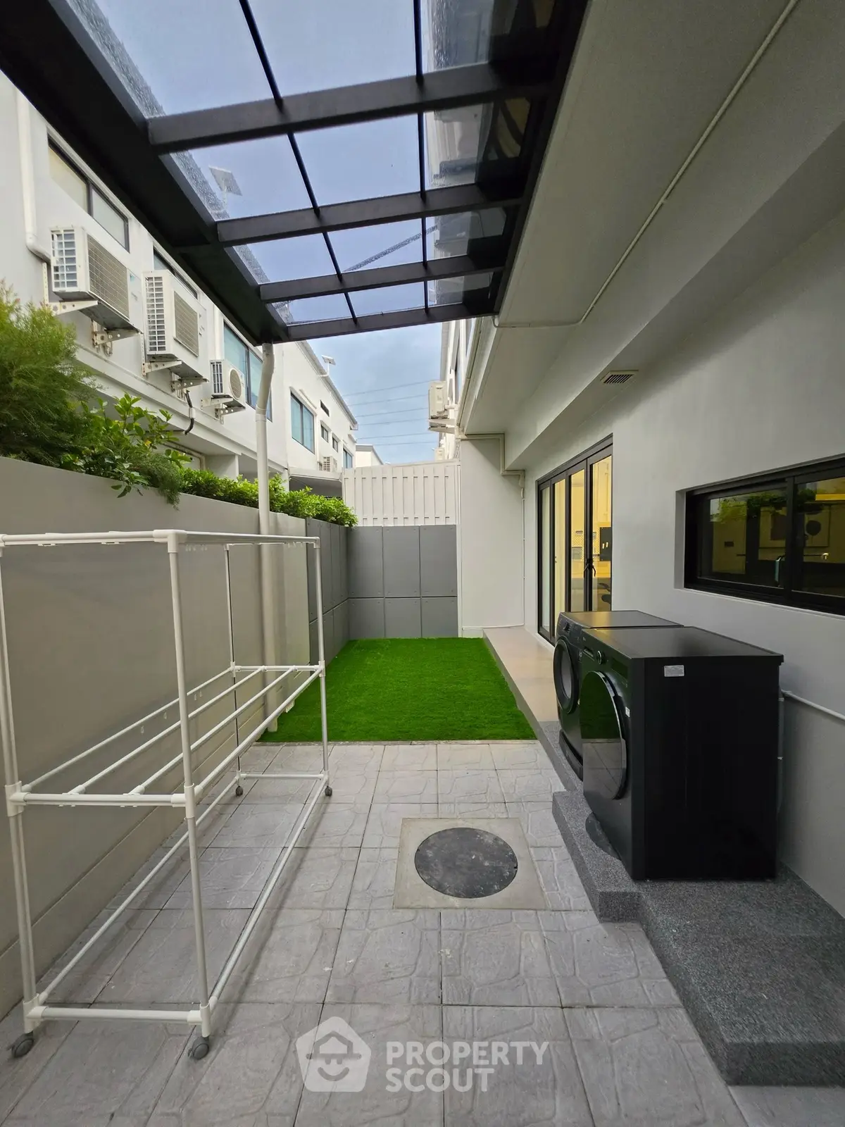 Modern outdoor laundry area with washing machine and drying rack in sleek residential setting.