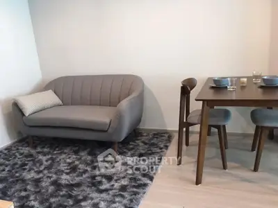 Modern living room with stylish gray sofa and dining set on plush rug