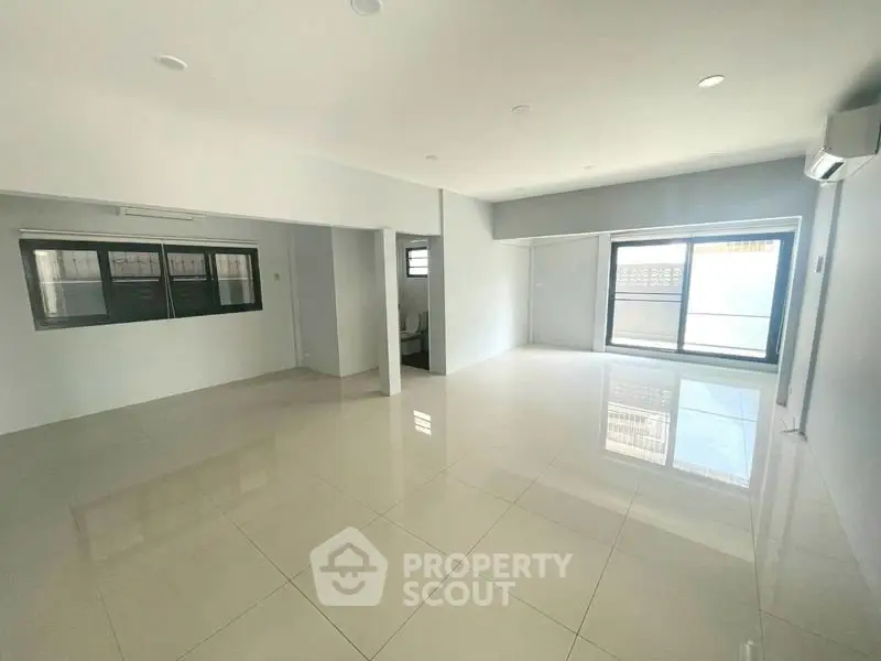 Spacious open-plan living area with large windows and modern tiled flooring.