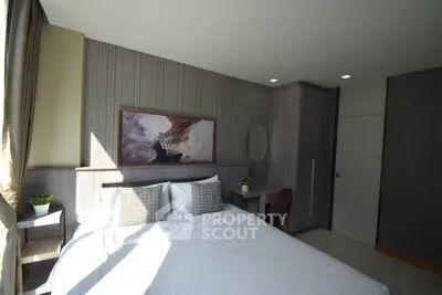 Modern bedroom with stylish decor and natural light, featuring a cozy bed and elegant furnishings.