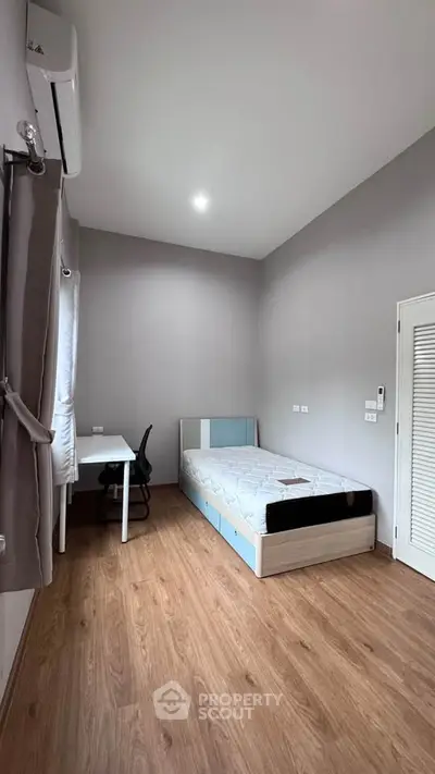 Modern minimalist bedroom with wooden flooring and sleek furniture