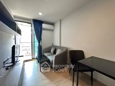Modern living room with balcony access, featuring sleek furniture and natural light.