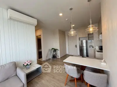 Modern living room with open kitchen, stylish lighting, and cozy dining area in a contemporary apartment.
