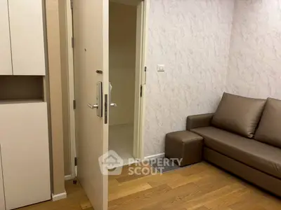 Cozy living room with modern sofa and open door, showcasing elegant wood flooring.