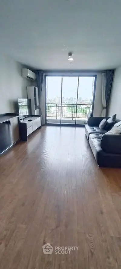 Spacious living room with modern furnishings and a stunning city view from the balcony.