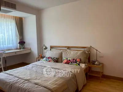 Cozy bedroom with natural light, wooden flooring, and stylish decor in modern apartment.