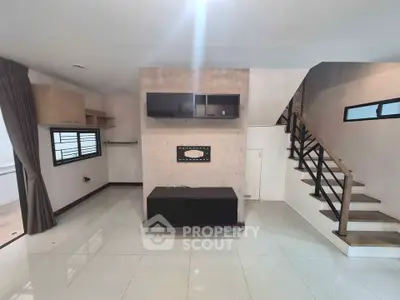 Spacious modern living room with sleek staircase and built-in entertainment unit.