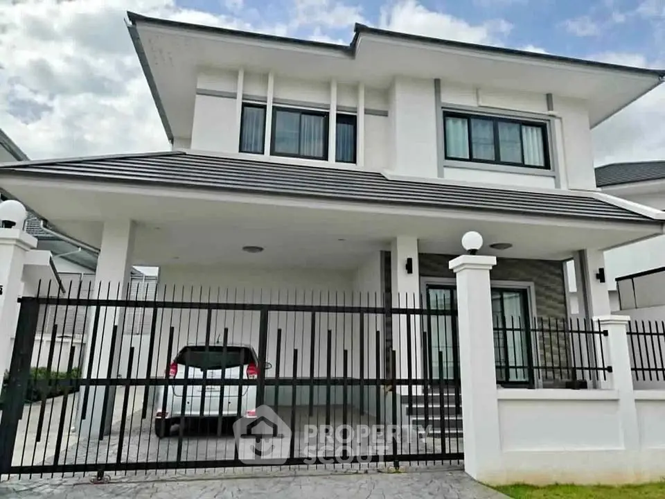 Modern two-story house with sleek design and gated driveway in a suburban neighborhood.