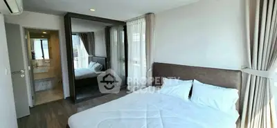 Modern bedroom with large mirror and en-suite bathroom in stylish apartment.