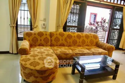 Elegant living room with patterned sofa and glass coffee table, bright natural light.